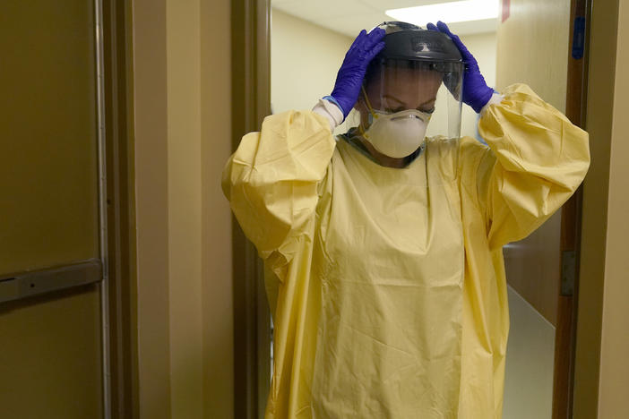 A nurse puts on personal protective equipment as she prepares to treat a COVID-19 patient last month at a rural Missouri hospital.