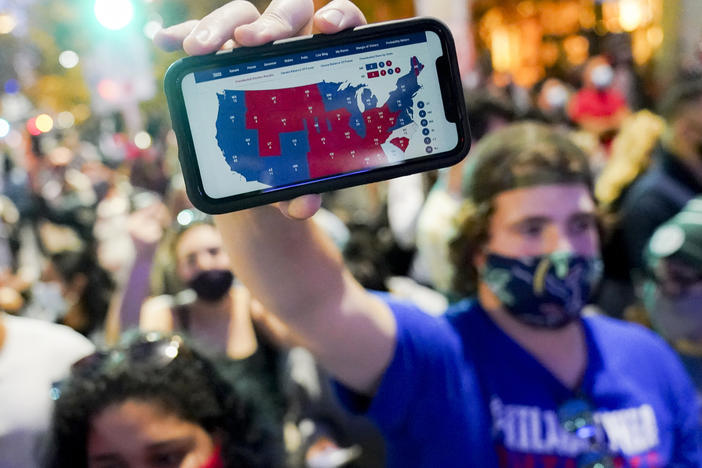 A supporter of President-elect Joe Biden holds up his mobile phone to display the Electoral College map outside the Philadelphia Convention Center after the 2020 presidential election is called on Nov. 7.