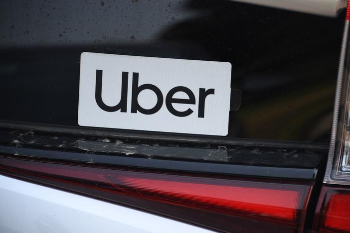 An Uber sticker is seen on a car at the start of a protest by ride share drivers on Aug. 20, in Los Angeles. Uber said it will sell its self-driving research unit to startup Aurora.