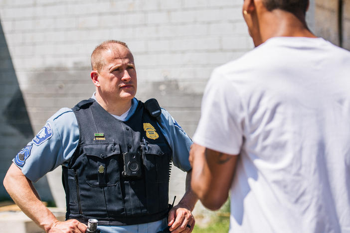 A man speaks with a Minneapolis Police officer at a crime scene on June 16. The Minneapolis City Council voted Thursday to shift $8 million in police funding to other services.
