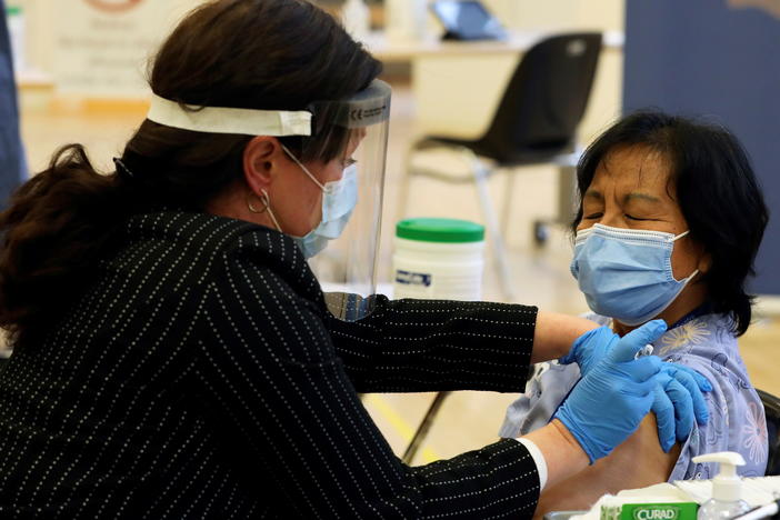A health care worker administers a Pfizer-BioNTech COVID-19 vaccine to personal support worker Anita Quidangen at The Michener Institute, in Toronto, Canada, on Monday. Quidangen was one of the first people in Canada to receive the shot.