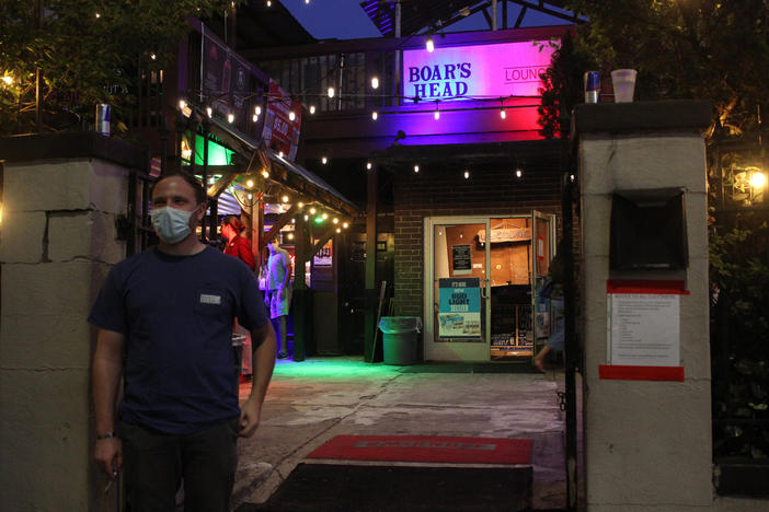 An employee of Boar's Head Lounge in downtown Athens, Georgia, wears a mask as he checks IDs at the door on June 1, 2020. Bars and nightclubs were allowed to reopen for the first time since March 24 following Gov. Brian Kemp's ordinance released on May 28