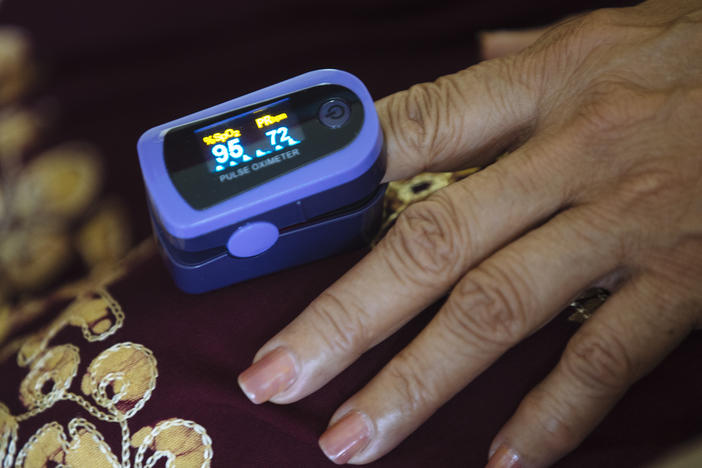 A paramedic uses a pulse oximeter to check a patient's vital signs during an August home visit in the Bronx borough of New York.