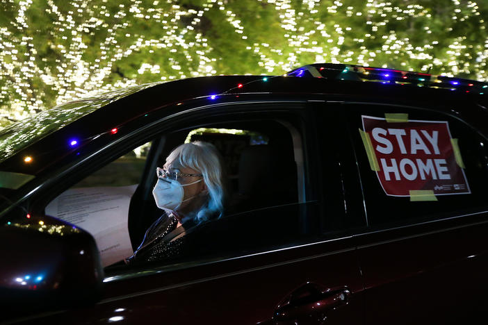 A "Stay Home" sign is taped to a driver's vehicle as she passes Christmas lights during a car caravan of nurses calling for people to remain home amid a coronavirus surge last month in El Paso, Texas.