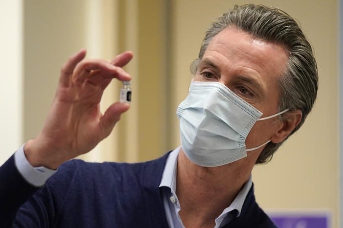 California Gov. Gavin Newsom holds up a vial of the Pfizer-BioNTech COVID-19 vaccine this week at a Los Angeles medical facility. Coronavirus cases continue to soar in the state as hospitals struggle to keep up with the surge.
