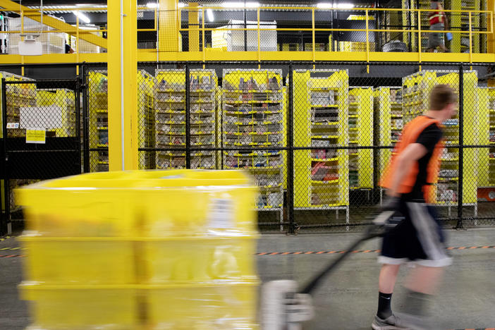 A worker pulls a pallet jack with plastic crates at an Amazon warehouse in Robbinsville, N.J. The company is facing its biggest labor battle yet with a unionization vote expected at a facility in Alabama.