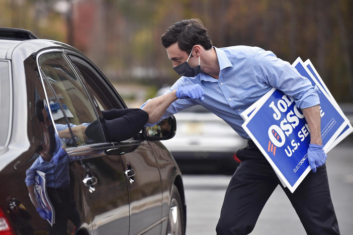 Jon Ossoff, a Georgia Democratic candidate for U.S. Senate, greets a supporter with an elbow bump at a drive-through event to pick up yard signs last month in Alpharetta, Ga. Ossoff is in a runoff with Republican David Perdue, the incumbent, for the U.S. Senate.