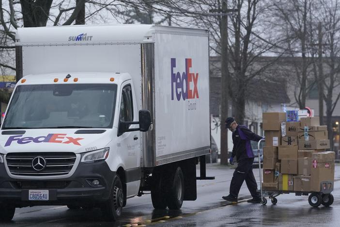 A driver with FedEx carries a package away from a van in Seattle. A huge increase in online shopping this year has demand for package delivery exceeding capacity this holiday season and stretching the delivery supply chain thin.