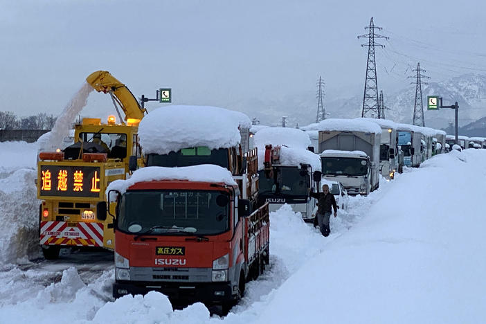 A snowplow clears a path beside cars stranded Friday on the snow-covered Kan-etsu Expressway in the city of Minamiuonuma in Japan's Niigata prefecture.