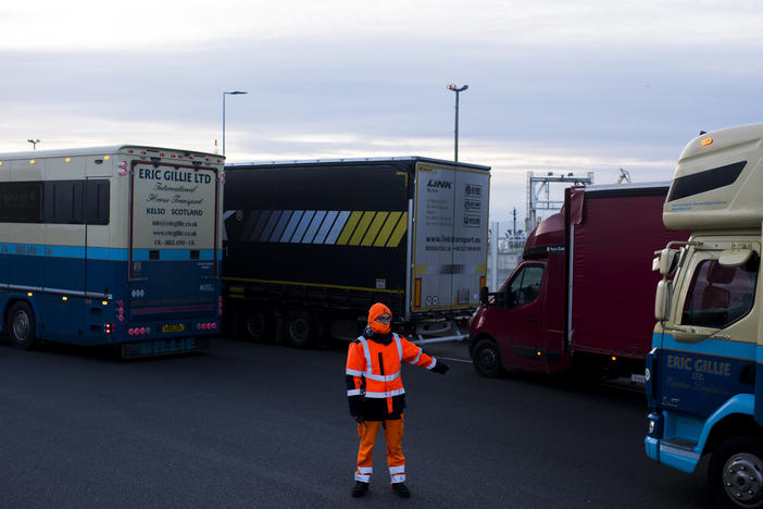 A worker directs trucks where to wait in line in order to board ferries to the United Kingdom in Calais, France. Twenty percent of British imports pass through the port of Calais.