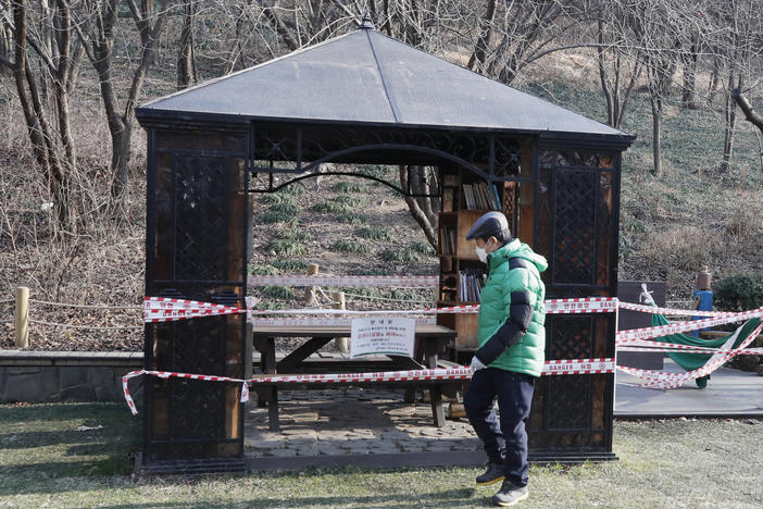 A man wearing a face mask walks past a rest area taped for social distancing as a precaution against the coronavirus in Seoul, South Korea, on Tuesday.