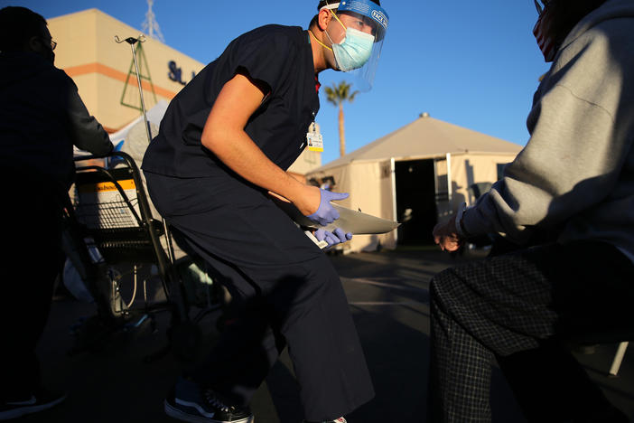 A California National Guard medic prepares to check the vital signs of an incoming patient in front of triage tents outside St. Mary Medical Center last week in Apple Valley amid a surge in COVID-19 patients in Southern California.