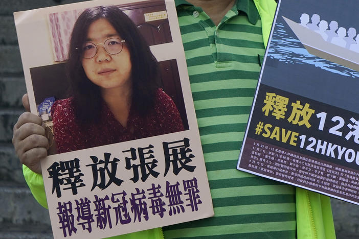 A pro-democracy activist holds placards with the picture of Chinese citizen journalist Zhang Zhan outside the Chinese central government's liaison office, in Hong Kong, Monday. Activists demand the release of Zhang, as well as the 12 Hong Kong activists detained at sea by Chinese authorities.