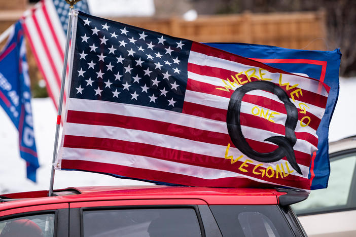 A car with a flag endorsing the QAnon conspiracy theory drives by as supporters of President Trump gather for a rally outside the Governor's Residence in St. Paul, Minn., on Nov. 14.