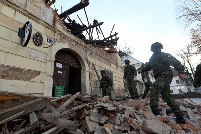 Croatian soldiers walk next to damaged buildings Tuesday in Petrinja, some 30 miles from the capital, Zagreb, after the town was hit by a 6.4 magnitude earthquake.