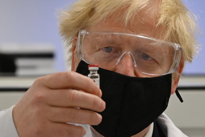U.K. Prime Minister Boris Johnson looks at the newly authorized AstraZeneca/Oxford University COVID-19 vaccine.