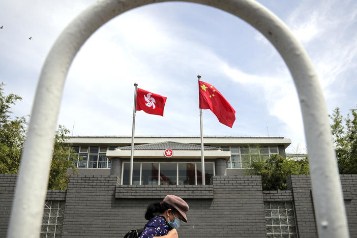 A woman wearing a face mask walks by the Government of Hong Kong Special Administrative Region office building in Beijing in June following the imposition of a national security law on Hong Kong. Ten Hong Kong fugitives were sentenced to prison Wednesday for illegally crossing international boundaries.