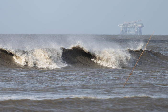 Hurricane Laura sends large waves crashing on a beach in Cameron, La., on Aug. 26 as an offshore oil rig appears in the distance. The most active hurricane season on record was just one of many challenges facing the oil industry this year — aside from the attention-grabbing crisis of the pandemic.