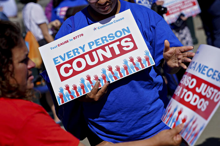 A demonstrator hands out a sign about the 2020 census outside the U.S. Supreme Court in Washington, D.C., in 2019. The Census Bureau is projecting the first set of census numbers won't be ready until February, Trump administration attorneys told a federal judge on Monday.