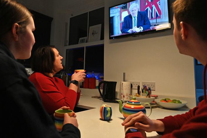 A family gathers around the television Monday in Liverpool, England, to watch Prime Minister Boris Johnson speak to the nation about the new lockdown.