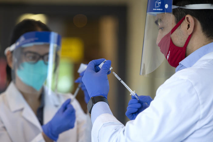 Pharmacists prepare doses of a COVID-19 vaccine last week at the Life Care Center of Kirkland in Kirkland, Wash. The nursing home was an early epicenter for coronavirus outbreaks in the United States.