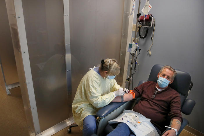 Nurse Janet Gilleran prepares to treat COVID-19 patient Mike Mokler with bamlanivimab, a monoclonal antibody drug from Eli Lilly, at the Respiratory Infection Clinic of Tufts Medical Center in Boston on Dec. 31, 2020.