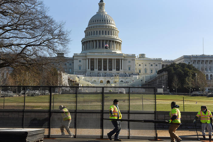 Workers install a fence in front of the U.S. Capitol on Thursday, one day after rioters stormed the building.