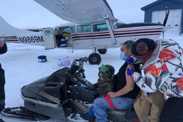 Sarah Lind, a nurse with Yukon-Kuskokwim Health Corp., Southwest Alaska's tribal health care provider, vaccinates James Evan in December. They're standing on the tarmac in the village of Napakiak, where Evan works for YKHC at the clinic.
