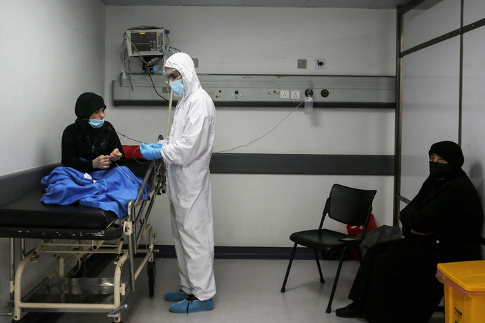 Inside an emergency room at Rafik Hariri Hospital on Nov. 17, a medic wearing full protective gear checks a woman who might have the coronavirus. Beirut hospitals are reaching maximum capacity amid an influx of coronavirus patients.