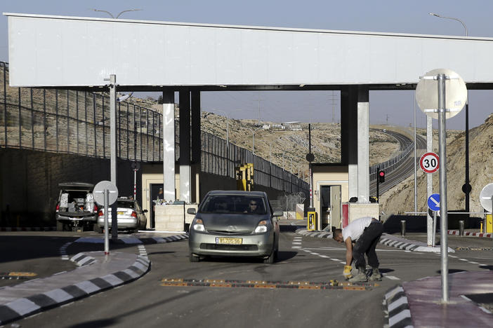 A checkpoint is seen on a West Bank highway near Jerusalem  which critics have branded an "apartheid highway." The highway features a large concrete wall segregating Israeli and Palestinian traffic.