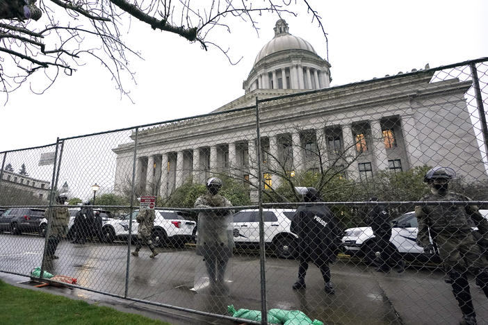 Members of the Washington National Guard stand near a fence surrounding the Capitol in Olympia, Wash., in anticipation of protests on Jan. 11, 2021.