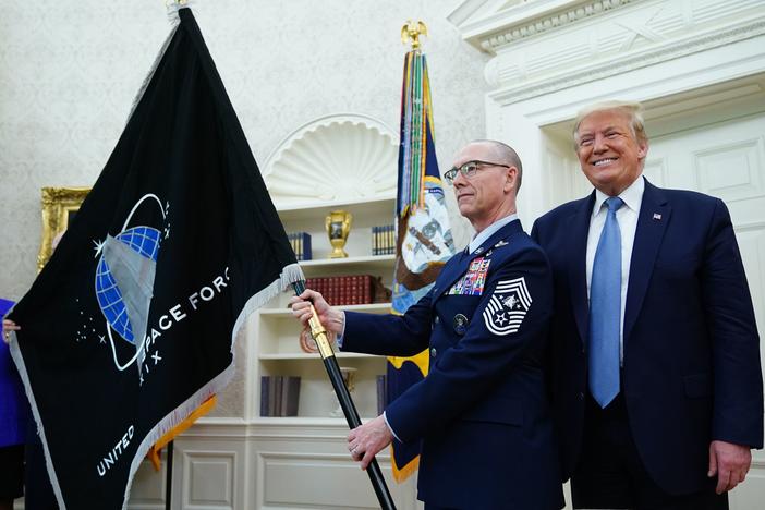 President Trump presedisplays the U.S. Space Force flag in the Oval Office last May. The new command plans to move its headquarters from a temporary location in Colorado to Alabama in 2023.