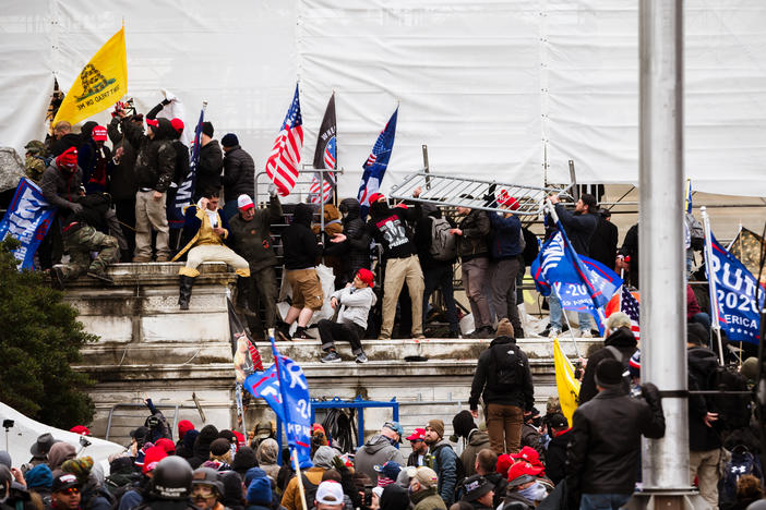 Pro-Trump extremists climb the walls of the U.S. Capitol on Jan. 6. The pro-Trump mob broke windows of the Capitol and clashed with police officers. Now there's debate about whether federal charges of seditious conspiracy should be used against some of the rioters.