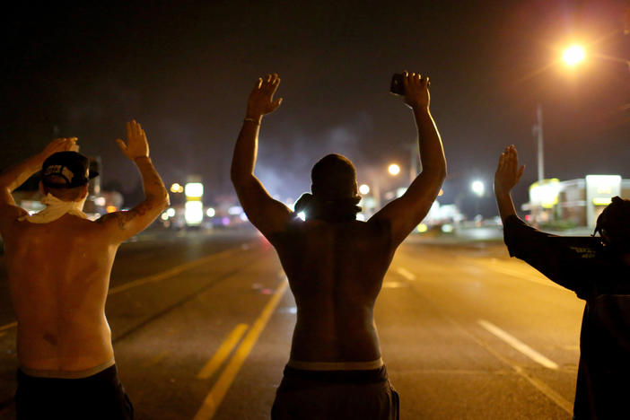 Demonstrators raise their arms and chant, "Hands up, don't shoot," in August 2014 as they protest the shooting death of Michael Brown in Ferguson, Mo.