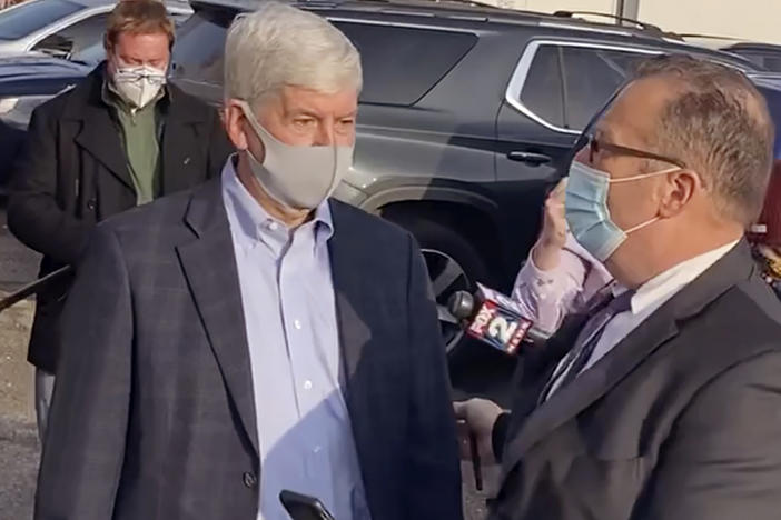 In this image taken from video, former Michigan Gov. Rick Snyder, left, with his lawyer, Brian Lennon, leave Genesee County Court in Flint, Mich., after a initial court appearance via Zoom on two misdemeanor counts of willful neglect of duty in connection to the Flint water crisis.