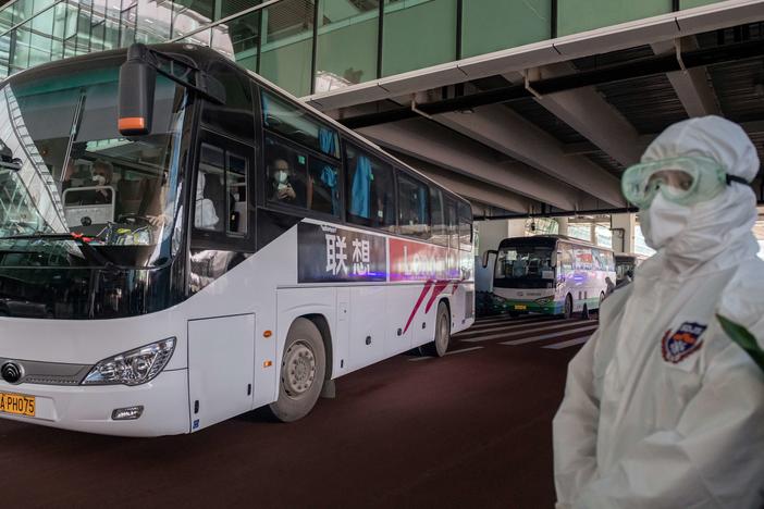 A bus carrying members of the World Health Organization team investigating the origins of the COVID-19 pandemic leaves Wuhan's airport following their arrival at a cordoned-off section in the international arrivals area on Thursday.
