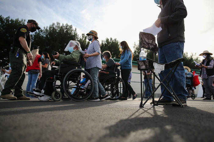 People lined up to receive the COVID-19 vaccine at a mass vaccination site in Disneyland's parking lot in Anaheim, Calif. on Jan. 13. The state says all residents 65 or older are now eligible to receive the vaccine.