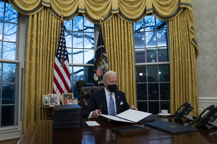 President Biden signs executive actions hours after his inauguration on Wednesday. He is expected to reverse several Trump-era policies.