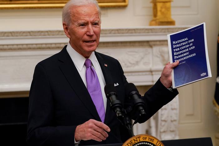President Joe Biden holds a booklet as he speaks about the coronavirus in the State Dining Room of the White House, Thursday.