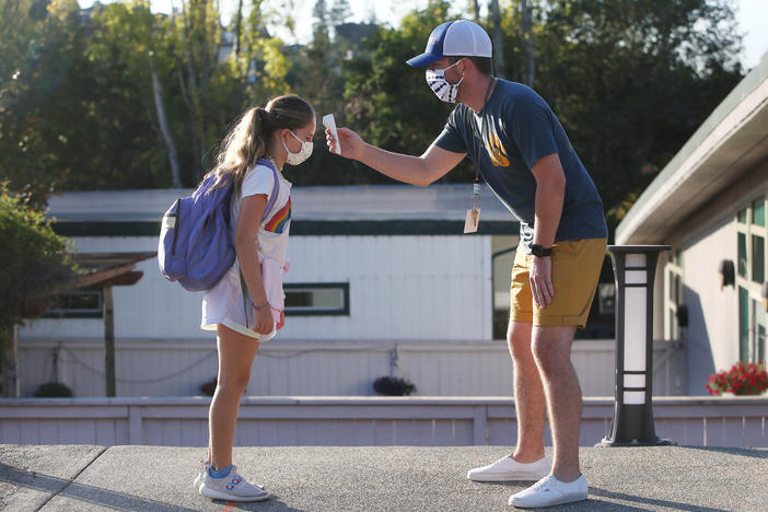 Nathan Grebil takes the temperature of a fourth-grader during a health screening in October at Bel Aire Elementary School in Tiburon, Calif.