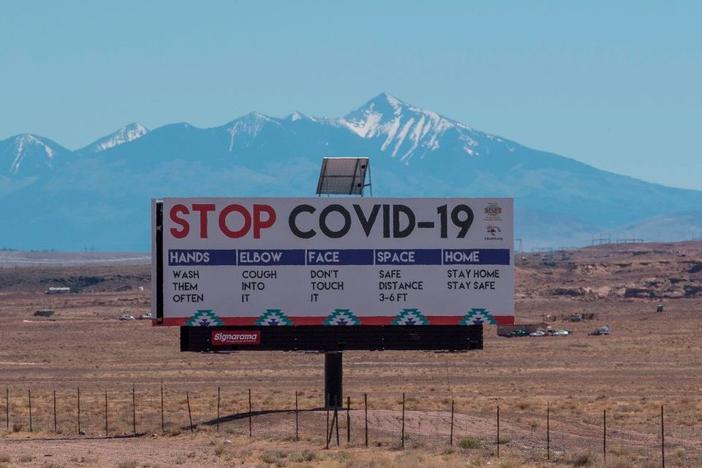 A sign warns against COVID-19 near the Navajo town of Tuba City, Ariz. As the pandemic rages across the U.S., mitigation measures continue to be critical to save lives.