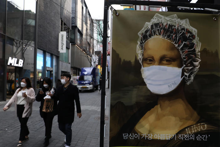 South Korea's KF94 mask does a good job concealing the <em>Mona Lisa</em>'s smile — but how effective is it at preventing coronavirus spread? Here, masked pedestrians stroll through a shopping district in Seoul.