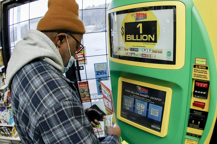 A patron, who did not want to give his name, uses the lottery ticket vending kiosk at a Smoker Friendly store to purchase tickets for the Mega Millions lottery drawing Friday in Cranberry Township, Pa.
