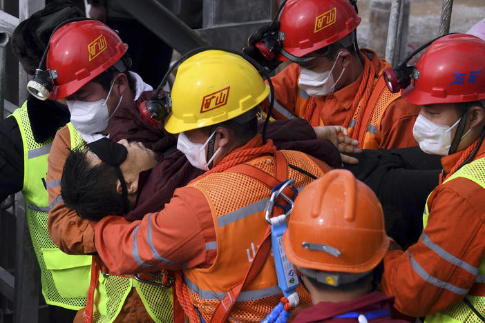 Rescuers carry a worker who was trapped in a gold mine to an ambulance in the city of Qixia in China's Shandong province. Eleven workers trapped for two weeks by an explosion inside the mine were brought safely to the surface on Sunday.