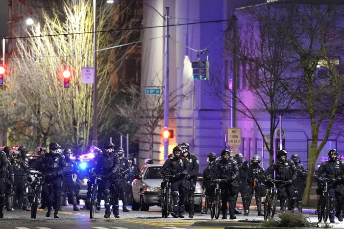 Police and other law enforcement officials stand in a line as protesters approach Sunday in the street in front of the City-County Building in Tacoma, Wash.