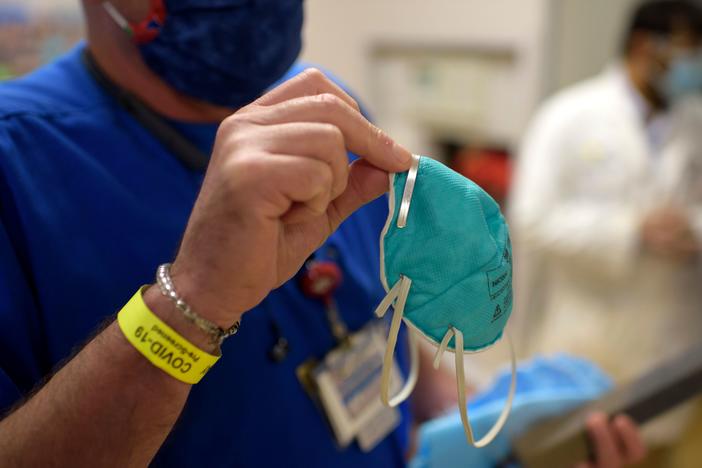 A health worker holds an N95 respirator in the emergency room at OakBend Medical Center in Richmond, Texas, in July. N95s are tested and approved by a federal agency as having demonstrated that they can filter out a minimum of 95% of airborne particles.