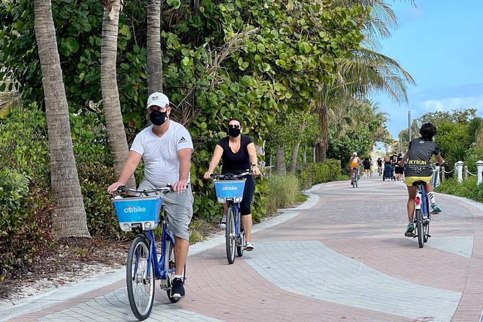 People bike along the beach in Miami on Dec. 20, 2020. "People are tired of being at home," one travel advisor says as an industry decimated by the pandemic begins to see small signs that a recovery might be on the way.