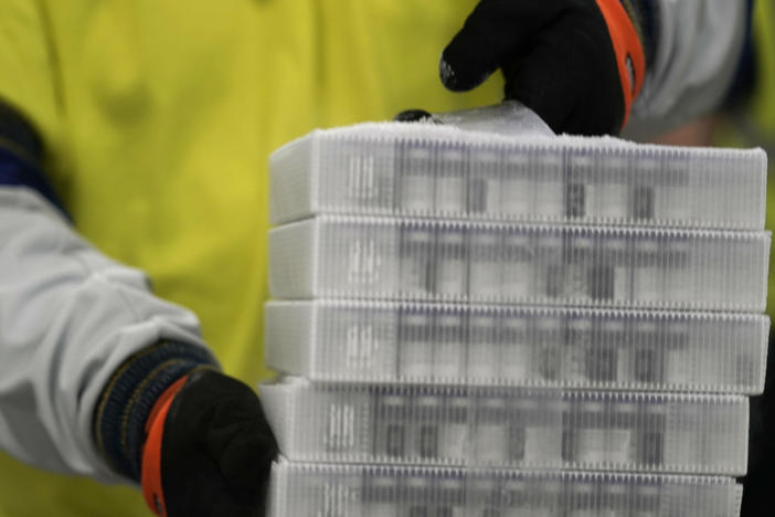 A worker carries boxes containing the Pfizer-BioNTech COVID-19 vaccine that were being prepared for shipment from a Pfizer facility in Portage, Mich., in December.