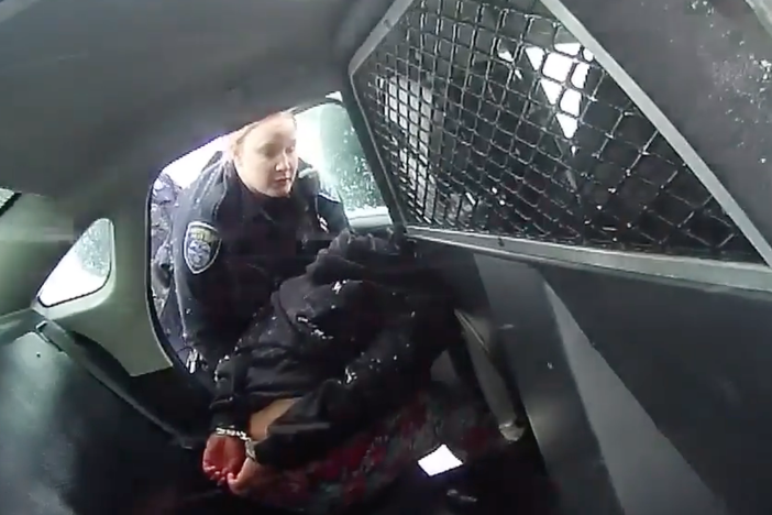 A frame from a Rochester Police Department body-camera video shows a girl in handcuffs in the back of a police cruiser.