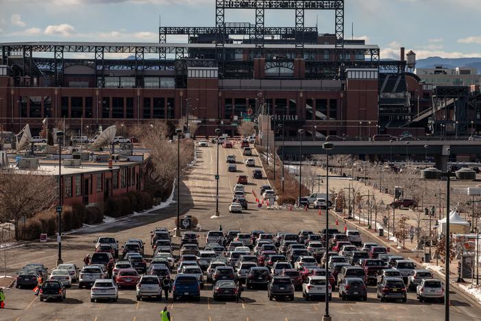 People line up for drive-through COVID-19 vaccination at Coors Field baseball stadium in Denver on Saturday.